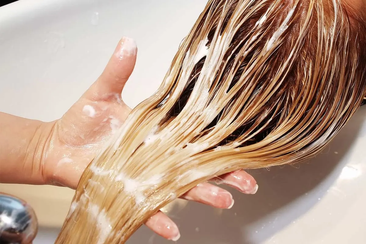 A blonde colour service being rinsed at the basin