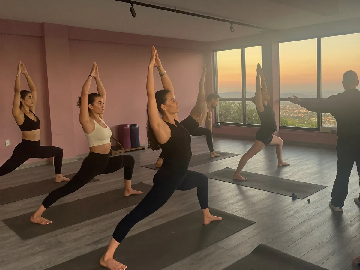 A group yoga class at sunrise, in a studio with lilac walls | Buiiild.com